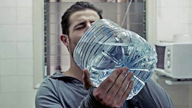 大きなペットボトルで水を飲む人